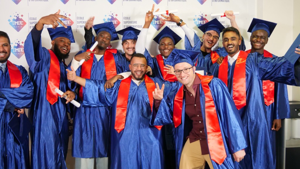 Groupe enthousiaste d'étudiants diplômés en informatique, habillés de toges et de toques bleues avec des écharpes rouges, levant les bras et souriant joyeusement après avoir reçu leurs diplômes.